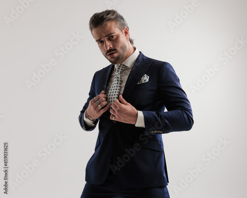 arrogant elegant fashion man looking forward while fixing navy blue suit © Viorel Sima