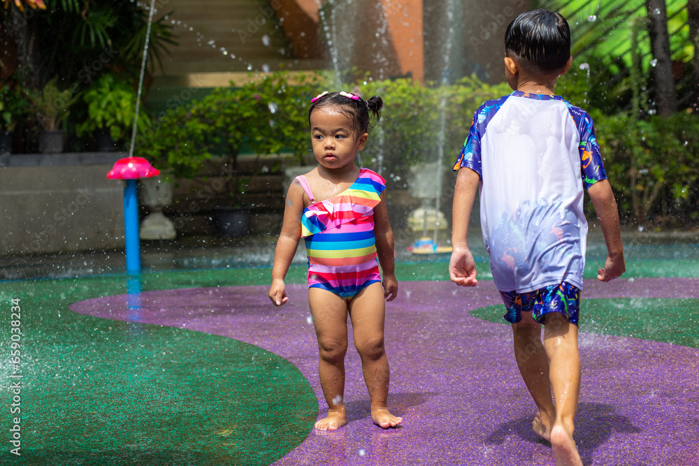 Obraz premium Happy child boy and girl enjoying water splash outdoor water park