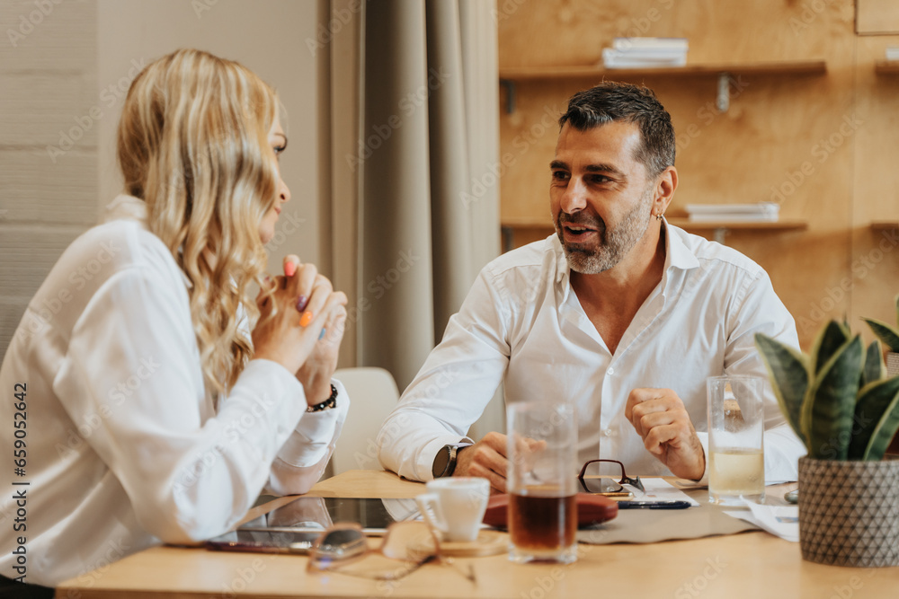 Beautiful, middle-aged, male and female business partners discussing the next project. Negotiations going well Beautiful, middle-aged, male and female business partners discussing the next project. Negotiations going well