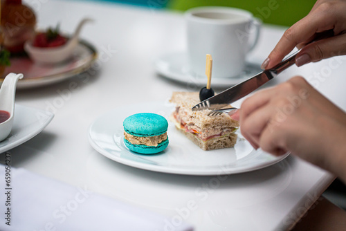 Human hands cutting a sandwich Sewing and knife in the hands of a girl cut a sandwich in a plate. A woman eats a sandwich in a light restaurant. Cutlery in the hands of a close-up. Cut the sandwich 