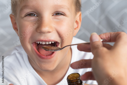 Cough syrup in bottle. Cute toddler boy holding in hands natural syrup. Health medicine concept. Pediatrician prescription for a child. photo