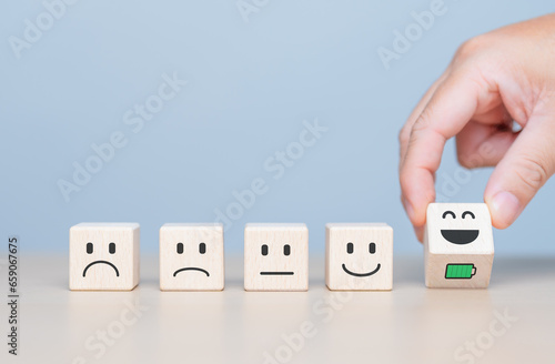 Wooden cube blocks with sad to smile face that flips to full battery icons. Mental health assessment. World Mental Health Day, Customer service rating experience, feedback emotion and satisfaction.