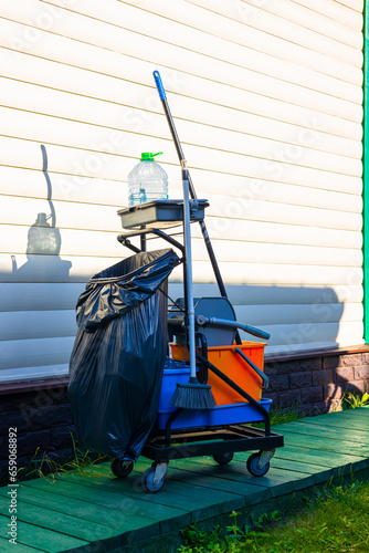 cleaning cart with tools stands near the house.