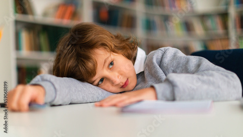 Bilde på lerret Bored schoolboy lying on desk during classroom lesson
