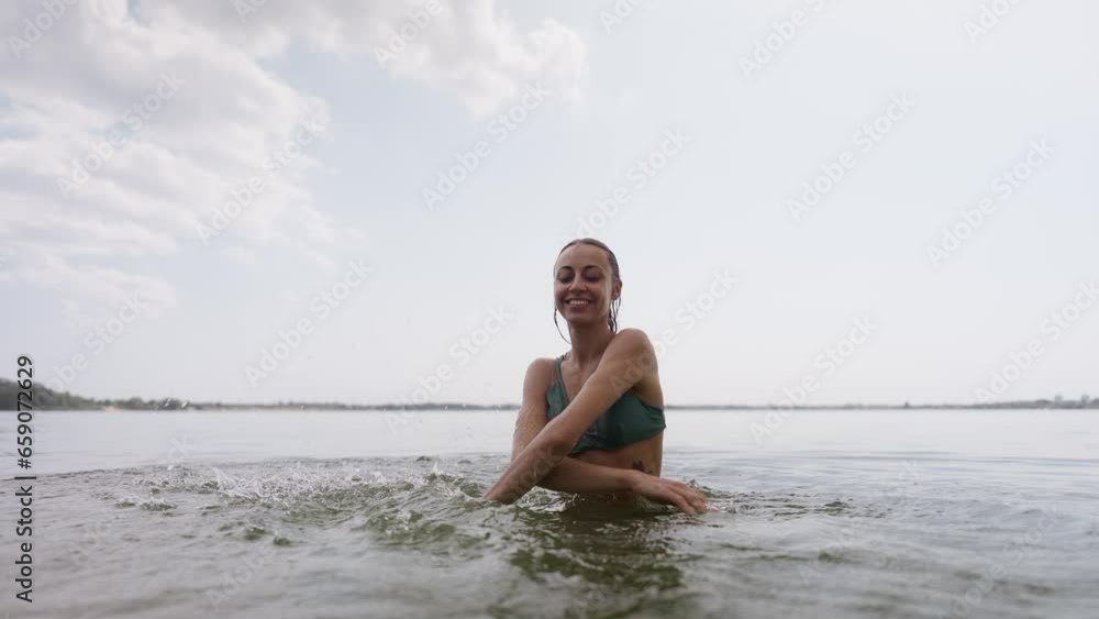beautiful joyful young sexy girl in green swimsuit having fun in lake water and splashing water by hands. Sporty body of beautiful woman in bikini on beach tropical background beautiful joyful young sexy girl in green swimsuit having fun in lake water and splashing water by hands. Sporty body of beautiful woman in bikini on beach tropical background