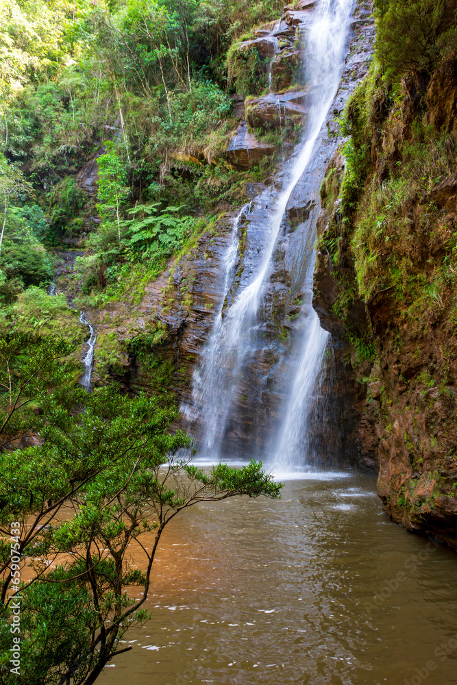 Fototapeta premium Beautiful waterfall among the dense vegetation of rainfoest and rocks in the state of Minas Gerais, Brazil