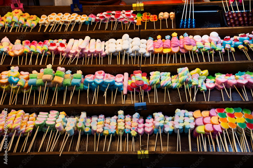 Colorful many variety snack marshmallow sweet dessert food and dipping in chocolate lava for thai people travelers buy eat in street market bazaar of temple annual festival in Nonthaburi, Thailand