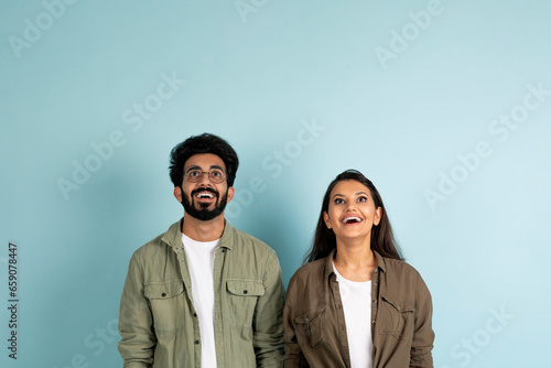 Amazed young multiracial couple looking up at copy space