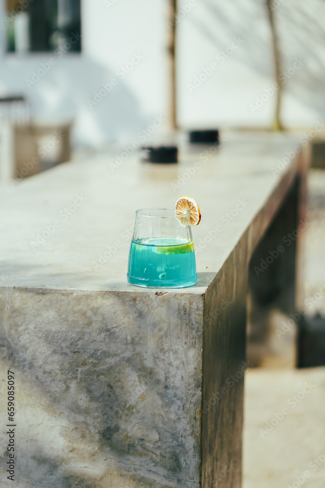 Blue cocktail with lemon on a stone terrace. Close up.