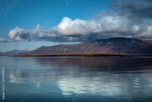 Landscape with Mount Esja and Atlantic ocean in Reykjavik, Iceland. Shining water, cloudy sky. 
