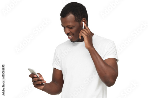 Young african american man surfing using mobile phone, listening to music with white wireless earphones