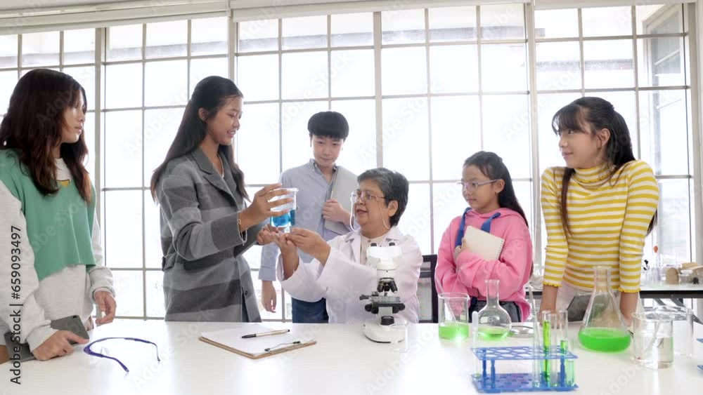 Senior 60s science teacher teaching group of Asian students looking microscope for chemical mixing research using modern technology laptop notebook, employment elderly people working in organization Senior 60s science teacher teaching group of Asian students looking microscope for chemical mixing research using modern technology laptop notebook, employment elderly people working in organization