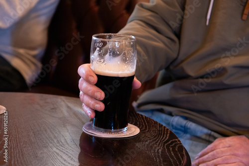 Obraz na płótnie Man's hand holding a pint of beer in a pub