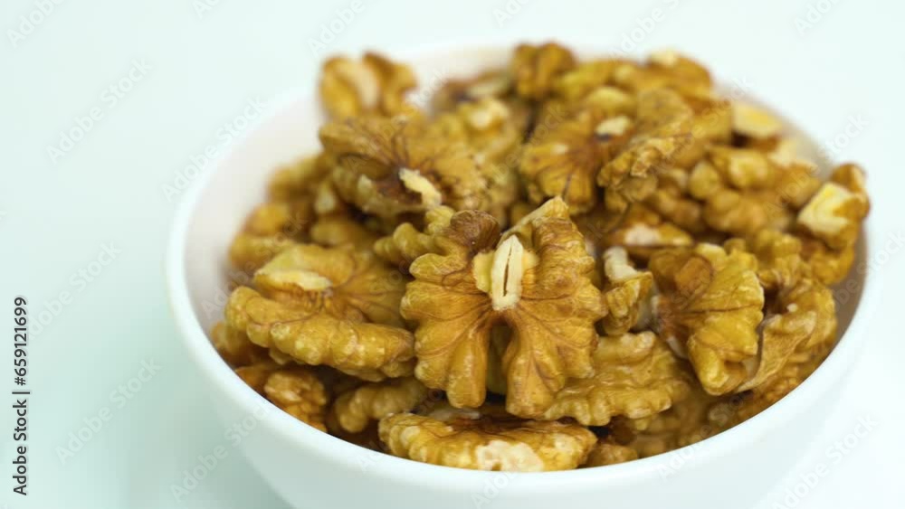 A white plate with peeled walnut kernels is spinning on the turntable. Close-up. View from above A white plate with peeled walnut kernels is spinning on the turntable. Close-up. View from above