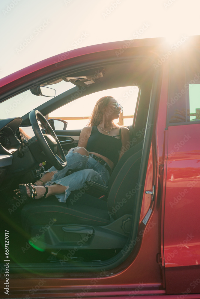 Pretty woman with sunglasses is posing inside of a car at sunset Pretty woman with sunglasses is posing inside of a car at sunset