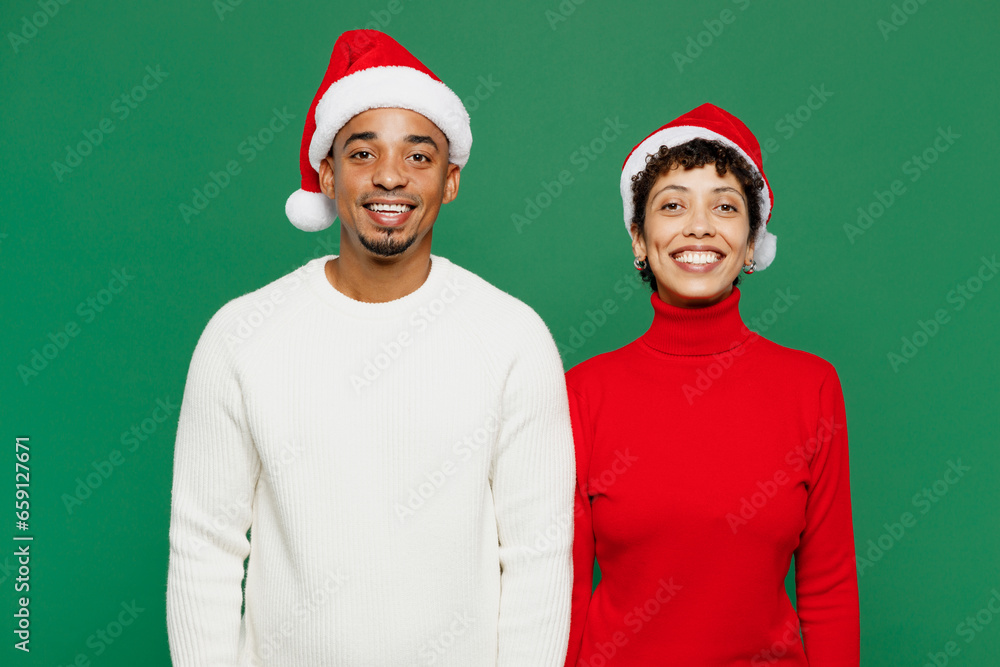 Merry smiling cheerful cool fun young couple friends man woman wear red casual clothes Santa hat posing look camera isolated on plain green background. Happy New Year 2024 Christmas holiday concept. Merry smiling cheerful cool fun young couple friends man woman wear red casual clothes Santa hat posing look camera isolated on plain green background. Happy New Year 2024 Christmas holiday concept.
