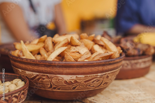 Close up of french fries, meat, barbecue for sale in traditional Ukrainian pottery at the international street food festival, selective focus. photo