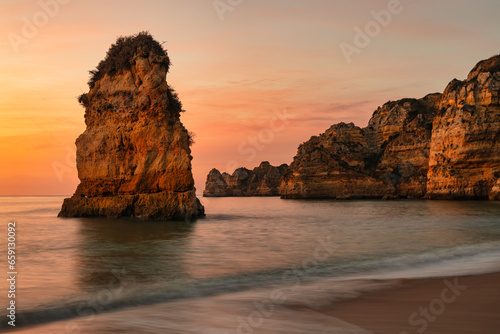 Scenic view of a rocky coastline against the sea at sunset (do camilo beach, algarve, portugal) photo
