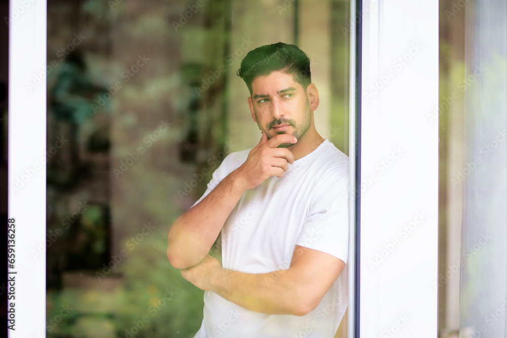 Close-up portrait of a man looking thoughtfully and standing behind windowpane Close-up portrait of a man looking thoughtfully and standing behind windowpane