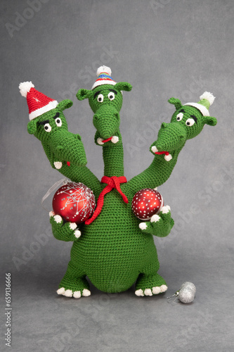 Three-headed dragon in New Year's hats and a red scarf knitted from green yarn