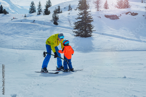 Obraz na plátně Father in skiing school glide backwards teach child to ski