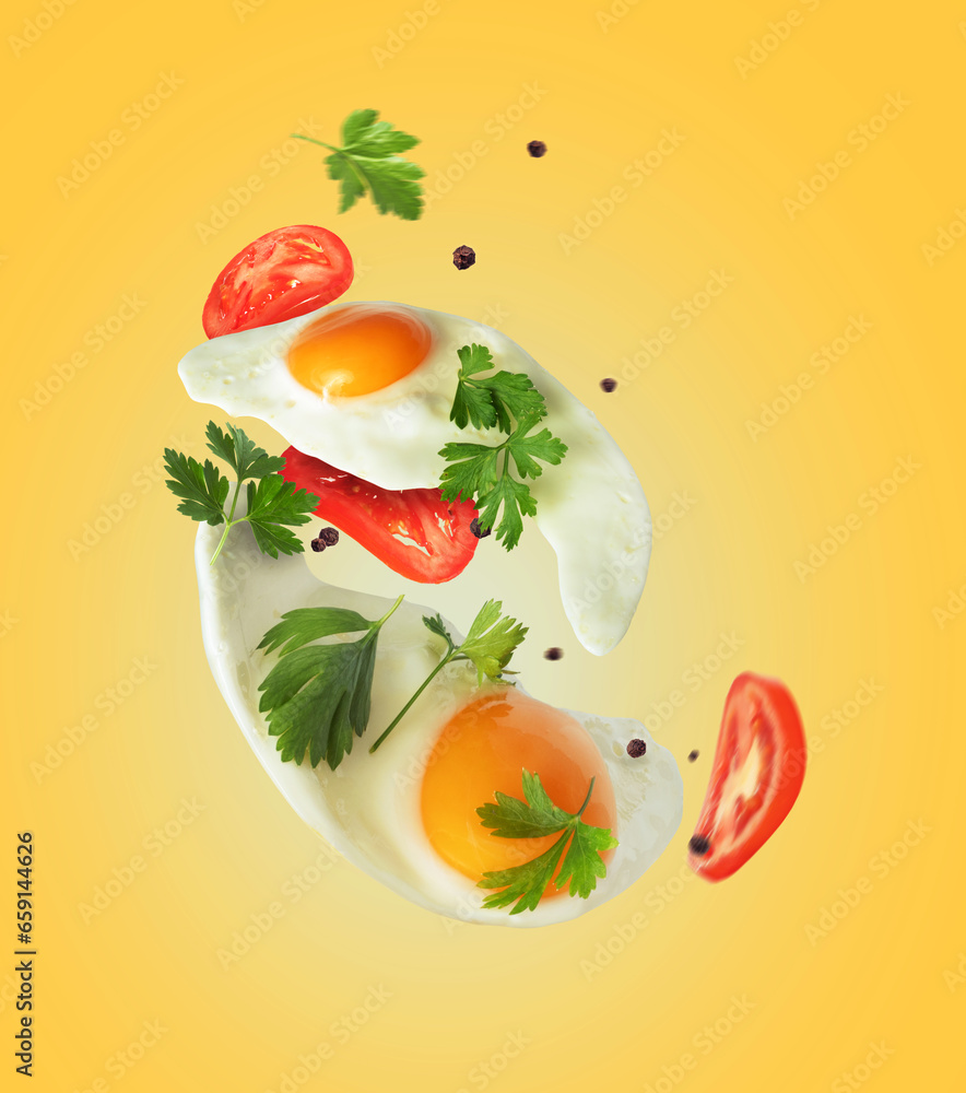 Two fried eggs with tomatoes and parsley in the air on a yellow background Two fried eggs with tomatoes and parsley in the air on a yellow background