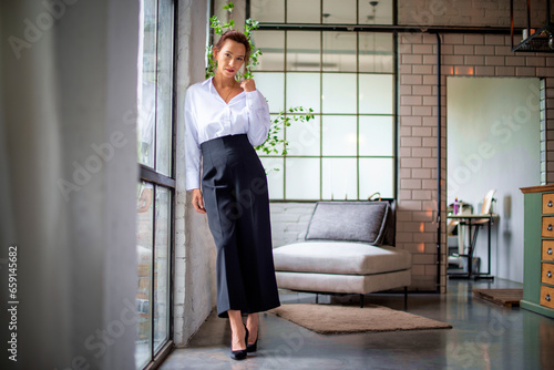 Full length shot of an attractive brunette haired woman standing at the window