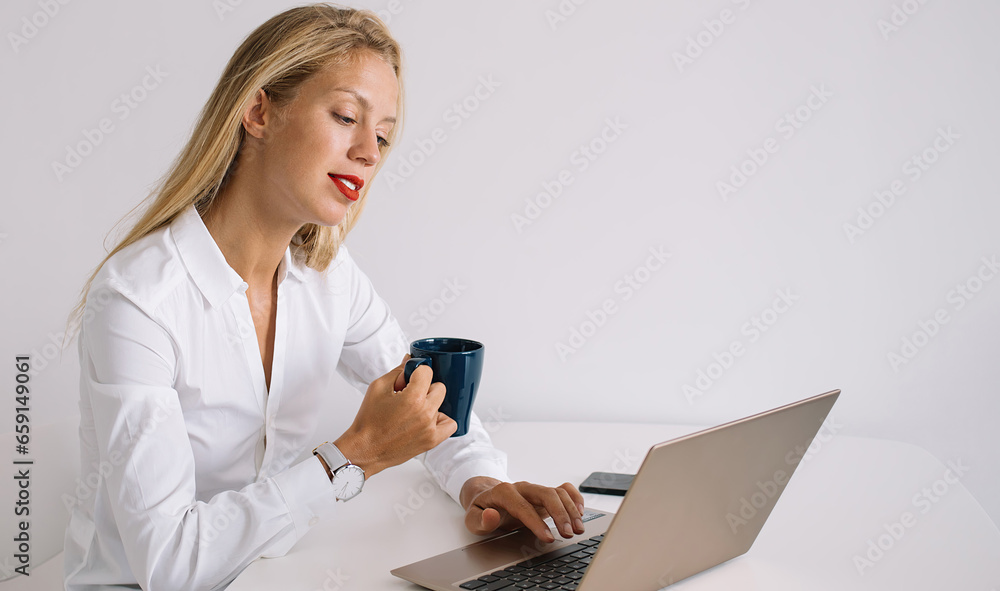 Young woman with coffee sitting and typing at laptop Young woman with coffee sitting and typing at laptop