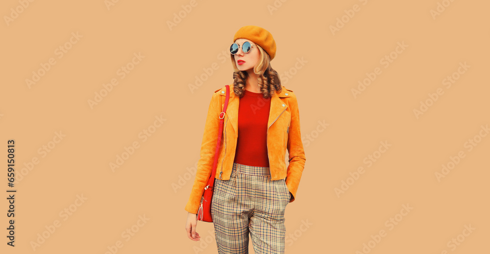 Autumn style outfit, beautiful stylish young woman posing with handbag looking away wearing orange french beret hat, jacket and round sunglasses on beige studio background Autumn style outfit, beautiful stylish young woman posing with handbag looking away wearing orange french beret hat, jacket and round sunglasses on beige studio background