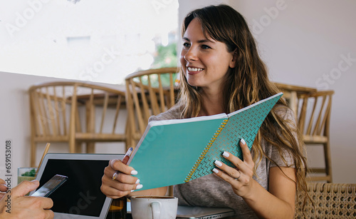 Female assistant showing opened notebook to bearded colleague