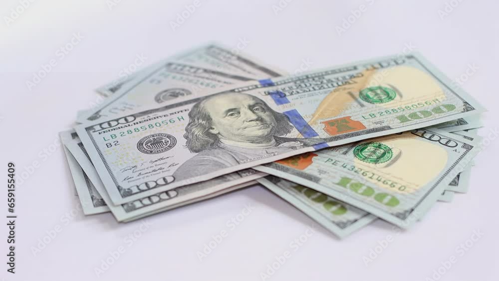 A man counts hundred dollar bills on a table on a white background close-up of hand. A man counts hundred dollar bills on a table on a white background close-up of hand.