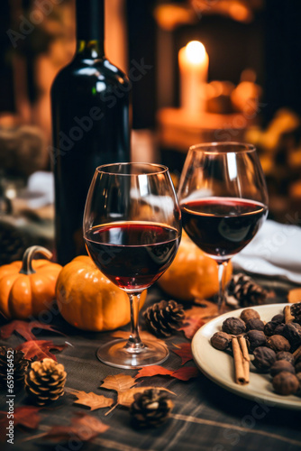 Pair of wine glasses and red wine bottle on a fall table with pumpkins and pinecones, vertical, Thanksgiving