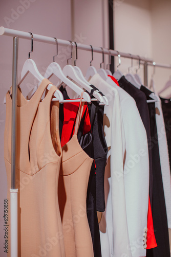 Designer fashion outfits hanging in a row at the backstage. Beige, white, red colors. Spring summer fashion collection