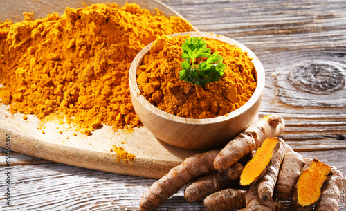 Composition with a bowl of ground turmeric and its fresh rhizome