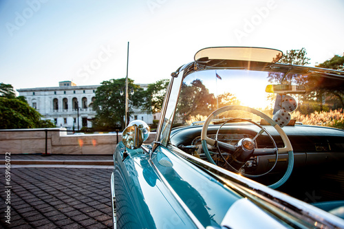 classic old convertible car parked in front of old public library building in Detroit at a nice sunny evening with sunsetting view 