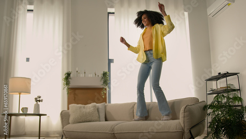Foto Funny African American woman happy girl at home dancing jumping have fun fooling