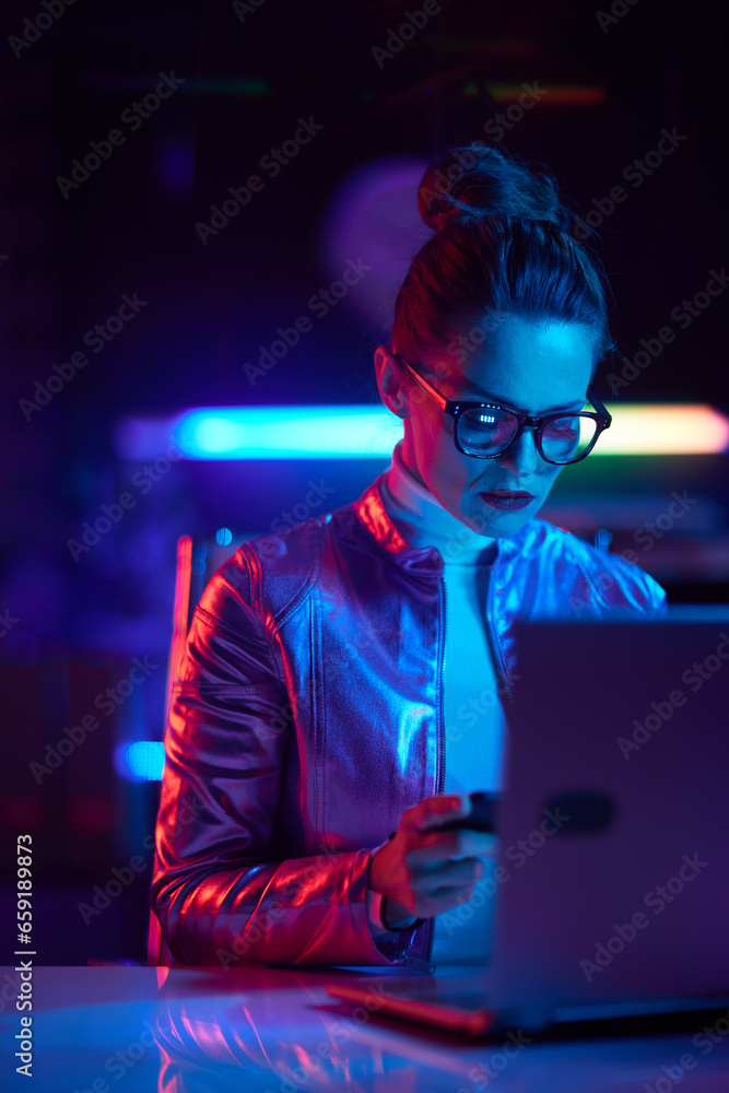 modern woman in glasses with laptop using smartphone modern woman in glasses with laptop using smartphone