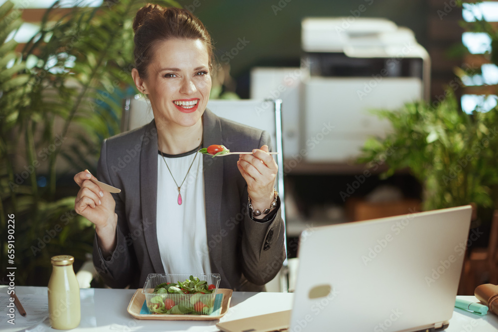 happy female employee in green office eating salad happy female employee in green office eating salad