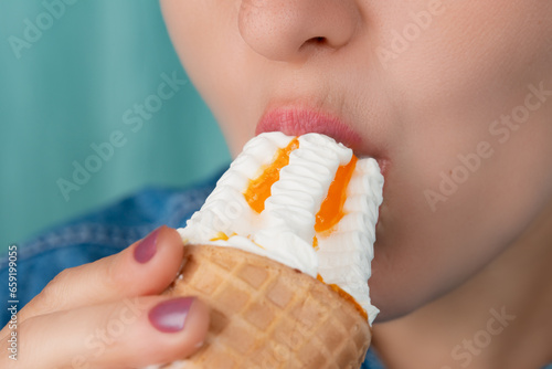 Close-up of a Caucasian woman's mouth biting an ice cream cone. Front three-quarter view. Low angle view. Indoors.
