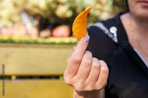 Woman's hand holding chips, snack and fast food concept. Selective focus on hands with blurred background