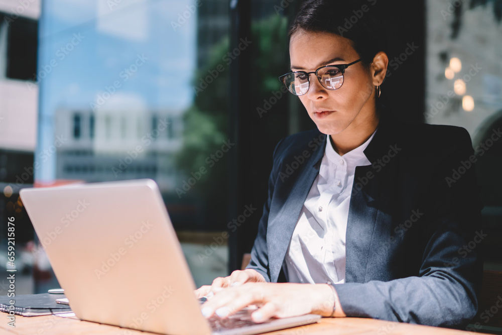 Fototapeta premium Female entrepreneur using laptop in street cafe
