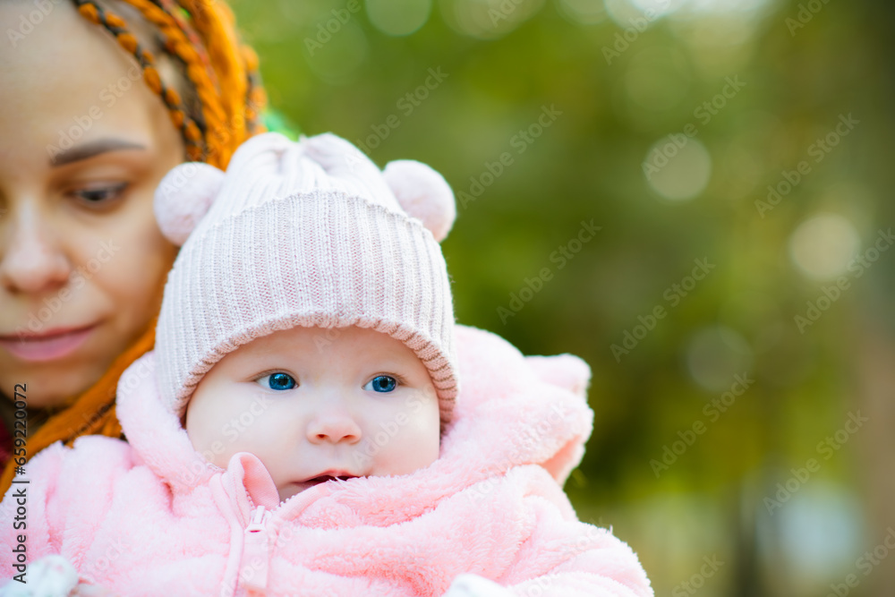 Young mother with her little daughter in the park. Focus on baby Young mother with her little daughter in the park. Focus on baby