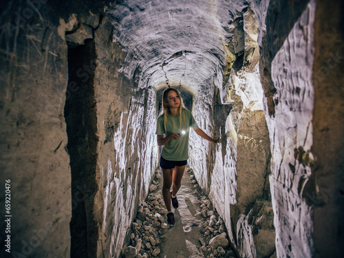 Girl with flashlight explores dark creepy abandoned underground chalky cave temple