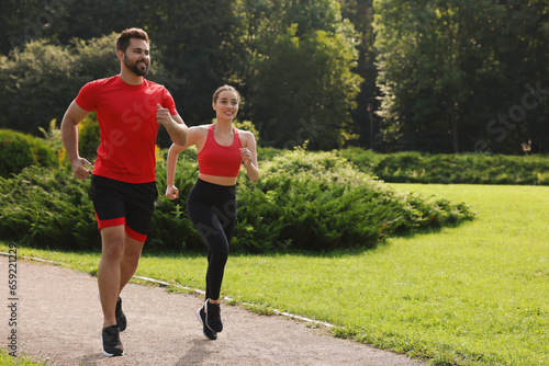 Healthy lifestyle. Happy couple running in park on sunny day, space for text