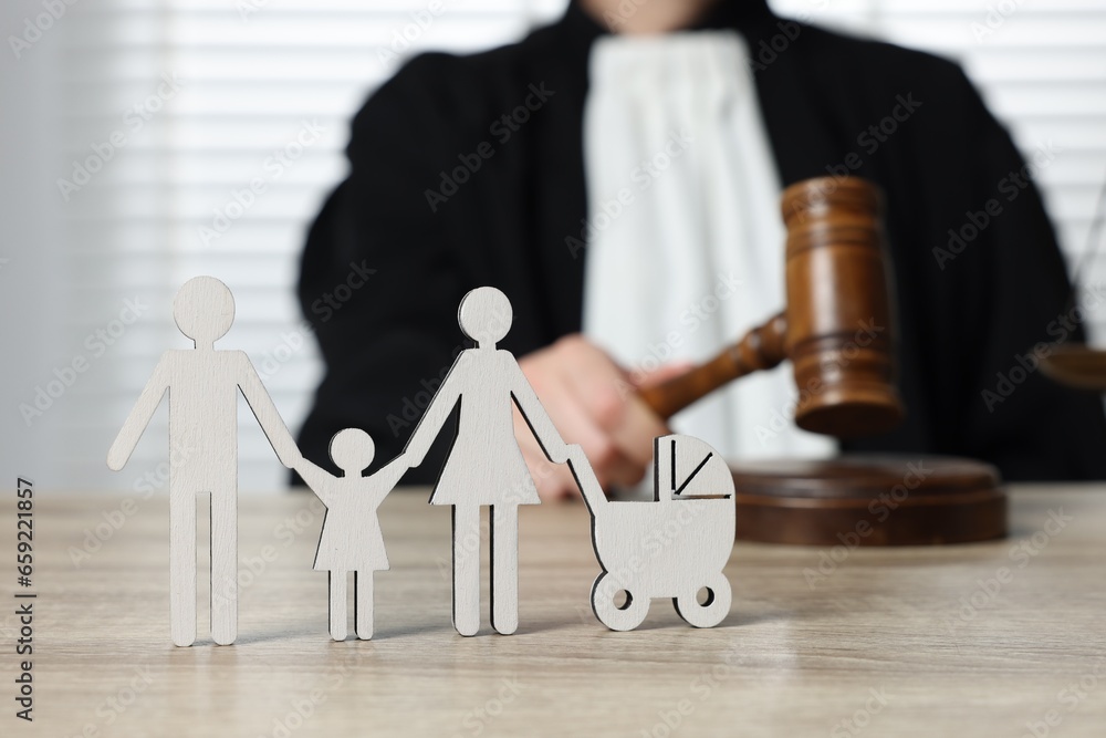 Family law. Judge with gavel sitting at wooden table, focus on figure of parents and children Family law. Judge with gavel sitting at wooden table, focus on figure of parents and children