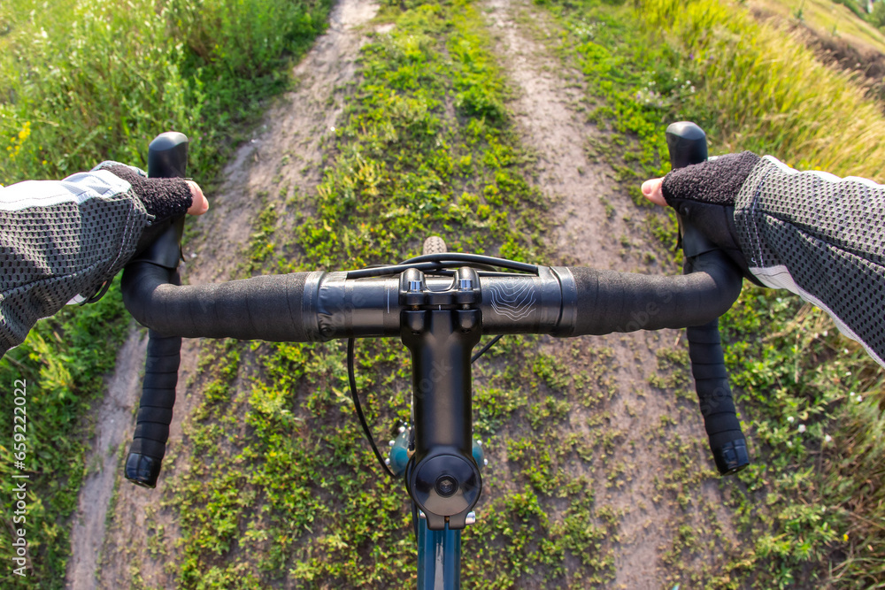 hands on the handlebars of a bicycle of a cyclist riding along a trail in nature. Point of view hands on the handlebars of a bicycle of a cyclist riding along a trail in nature. Point of view