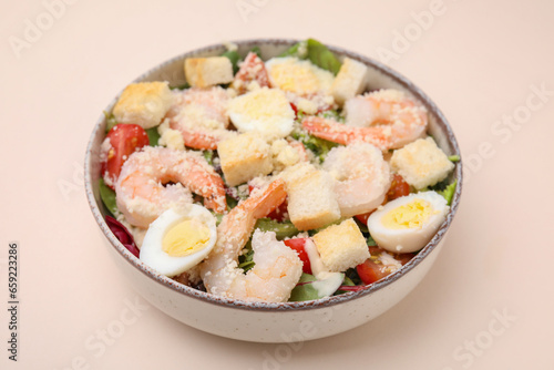 Delicious Caesar salad with shrimps on beige background, closeup