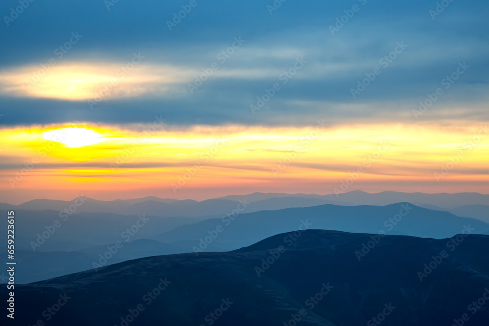 Colorful clouds in the sky at sunset against the backdrop of a mountainous forest area.