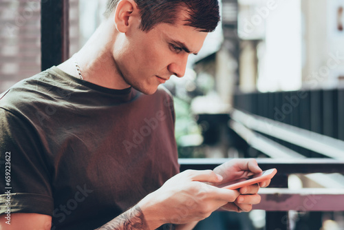 Serious male browsing phone on terrace of cafe
