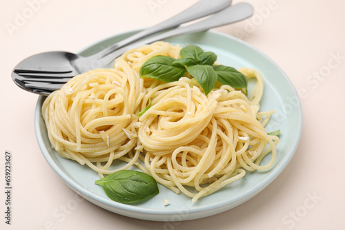 Delicious pasta with brie cheese and basil leaves on beige table, closeup